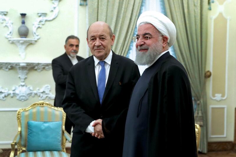 In this photo released by an official website of the office of the Iranian Presidency, President Hassan Rouhani, right, welcomes French Foreign Minister Jean-Yves Le Drian at the start of their meeting, in Tehran, Iran, Monday, March 5, 2018. Le Drian met stiff resistance from his Iranian counterpart, who said Western arms deals had turned the Middle East into a "gunpowder depot." His one-day trip Monday highlighted the challenge Paris faces in challenging Iran while at the same time trying to keep the 2015 nuclear deal with world powers intact. (Iranian Presidency Office via AP)