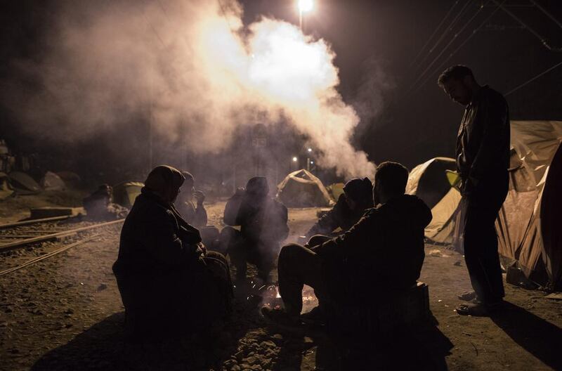 Refugees sit around a fire at a camp on the Greek-Macedonian border. Georgi Licovski / EPA