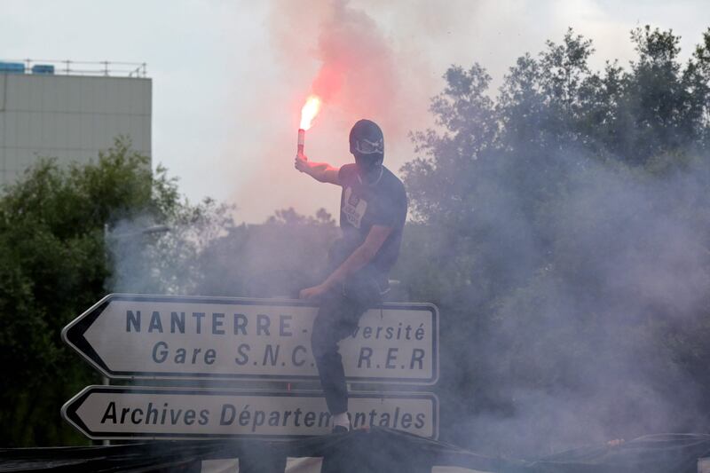 A protester waves a flare during the march for Nahel. AFP