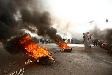 A Sudanese protester walks past burning tyres as military forces tried to disperse a sit-in outside Khartoum's army headquarters on June 3, 2019. AFP