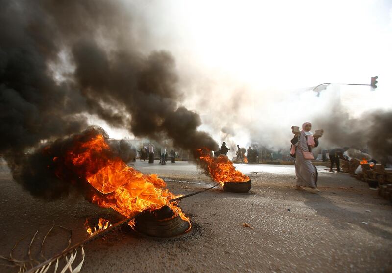 A Sudanese protester walks past burning tyres as military forces tried to disperse a sit-in outside Khartoum's army headquarters on June 3, 2019. - At least two people were killed Monday as Sudan's military council tried to break up a sit-in outside Khartoum's army headquarters, a doctors' committee said as gunfire was heard from the protest site. (Photo by Ashraf SHAZLY / AFP)