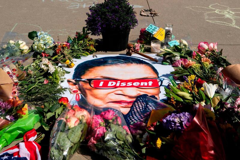 A banner with flowers are pictured at a makeshift memorial outside of the US Supreme Court as people pay their respects to Ruth Bader Ginsburg in Washington, DC on September 19, 2020. US President Donald Trump vowed to quickly nominate a successor, likely a woman, to replace late Supreme Court Justice Ruth Bader Ginsburg, only a day after the death of the liberal stalwart. / AFP / Jose Luis Magana
