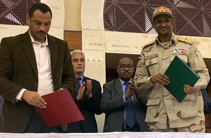 Sudanese deputy chief of the ruling miliary council Mohamed Hamdan Dagalo (R) and protest movement Alliance for Freedom and Changes leader Ahmad al-Rabiah stand after inking an agreement before African Union and Ethiopian mediators in Khartoum early on July 17, 2019. Sudan's protesters and ruling generals inked a power sharing deal, paving the way for a civilian administration, a key demand of demonstrators since president Omar al-Bashir was deposed in April. The two sides initialled a document called the "Political Declaration", an AFP correspondent reported, after intense talks through the night over fine details of the agreement.
 / AFP / Haitham EL-TABEI
