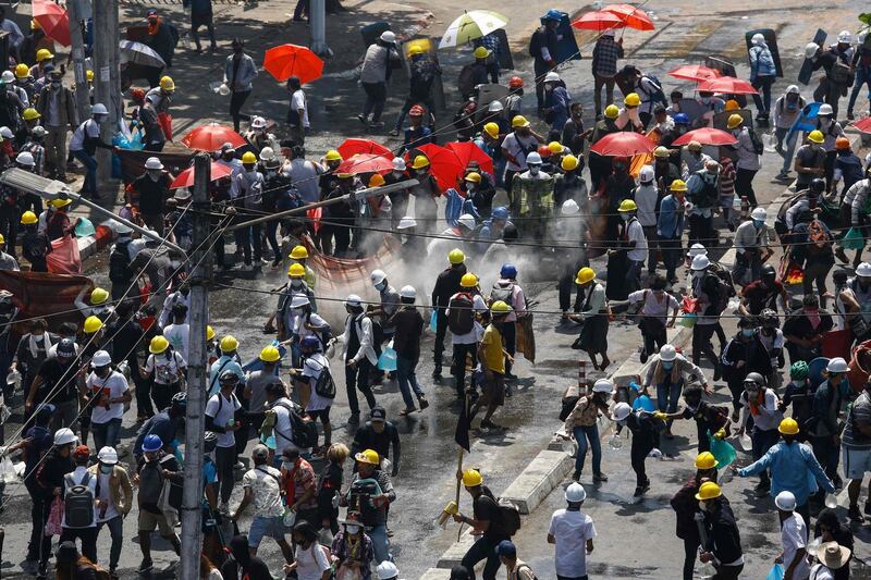 Protesters react after tear gas is fired during a demonstration against the military coup in Yangon. AFP