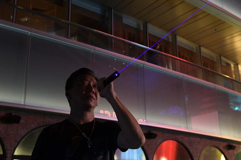 A pro-democracy demonstrator aims the beeam of a laser pen towards Lion Rock as others form a human chain on Victoria Peak in Hong Kong on September 13, 2019. - Thousands of Hong Kong pro-democracy activists used torches, lanterns and laser pens to light up two of the city's best-known hillsides on September 13 night in an eye-catching protest alongside an annual festival. The evening of September 13 marks the start of the mid-autumn festival, one of the most important dates in the Chinese calendar, and is traditionally a time for thanksgiving, spending time with family and praying for good fortune. (Photo by Nicolas ASFOURI / AFP)