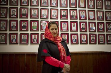 Fawzia Koofi, a government peace negotiator and former member of parliament, stands before a wall with photos of Afghan MPs. AP Photo