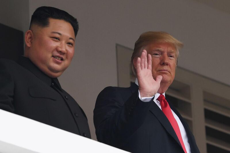 US President Donald Trump waves as he and North Korea leader Kim Jong Un look on from a veranda. Saul Loeb / AFP