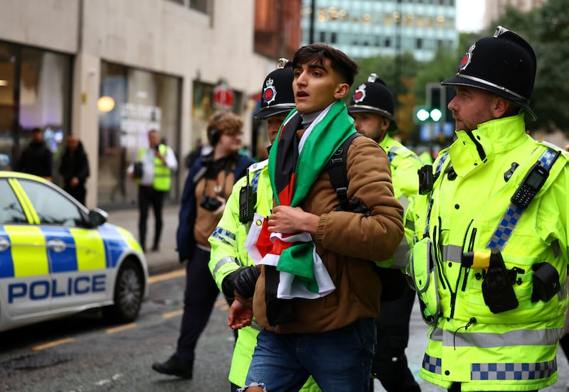 Police detain a man with a Palestinian flag at a vigil for Israel held in Manchester. Reuters