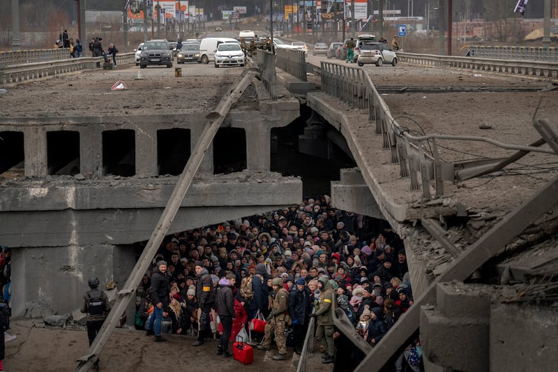 Ukrainians under a destroyed bridge as they try to cross the Irpin river on the outskirts of Kyiv in March 2022. AP