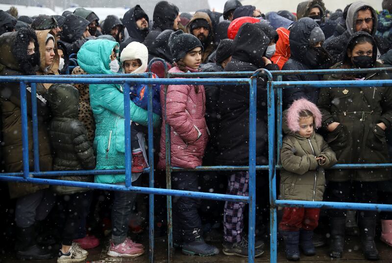 Migrants gather during snowfall at the warehouse where some are staying on the Belarusian side of the border with Poland. Reuters