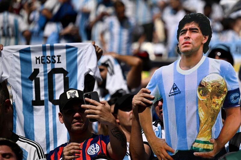 Argentina supporters hold up a jersey with Lionel Messi number 10 and a cutout of football legend Diego Maradona before the start of the match. AFP
