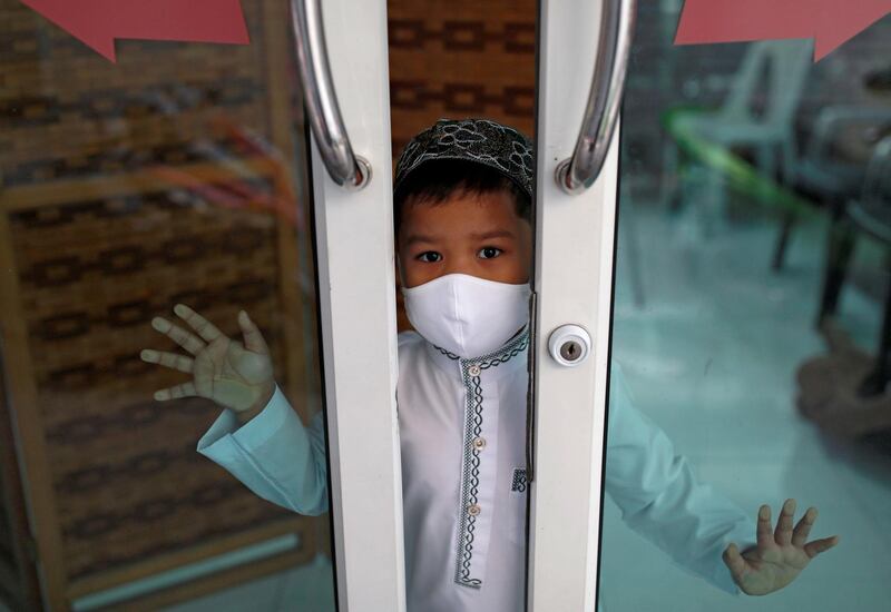 A Muslim boy wearing a protective face mask looks into a closed mosque on the first day of Ramadan, in Bangkok, Thailand on April 24, 2020. Reuters