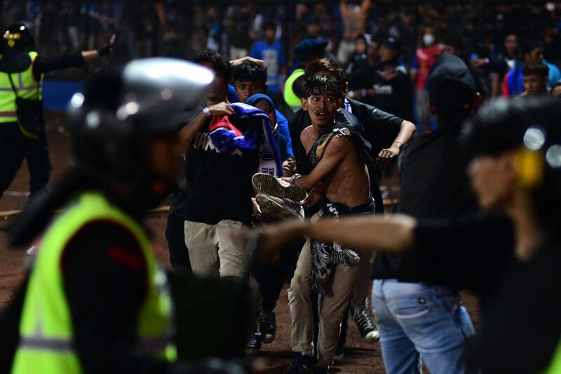 A group of people carry a man at Kanjuruhan Stadium during a stampede which killed 129 people. AFP