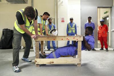 DUBAI ,  UNITED ARAB EMIRATES , JULY 3 – 2019 :- Hannes Loubser , fitness instructor with Iconic ( left ) looking at the Richmond Tawiah , construction worker who is doing exercise during the fitness training session at the DEWA Sub Station near the International City in Dubai. ( Pawan Singh / The National ) For Lifestyle . Story by Melanie Swan