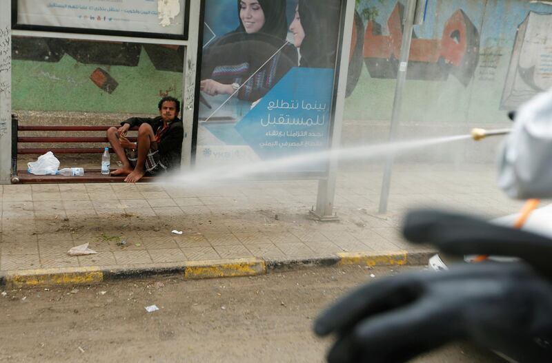 A man sits in an advertising frame as health workers disinfect a street in Sanaa, Yemen. Reuters