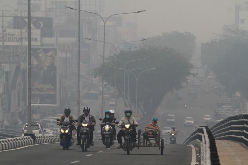 Motorists ride through a road blanketed by haze from wildfires in Pekanbaru, Riau province, Indonesia. AP Photo