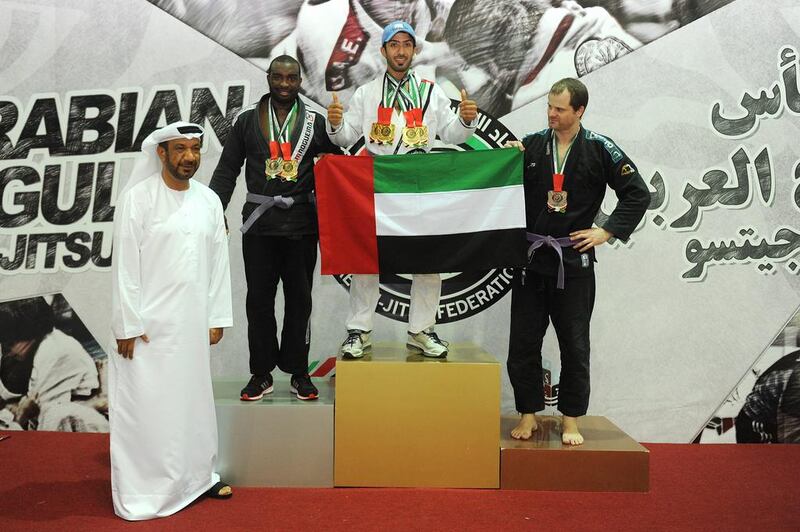 Gold medal winner Ahmed Suhail Al Ketbi gets a hand from the silver and bronze medallists in displaying the UAE flag on the podium. Abdullateef Al Marzouqi / Al Ittihad