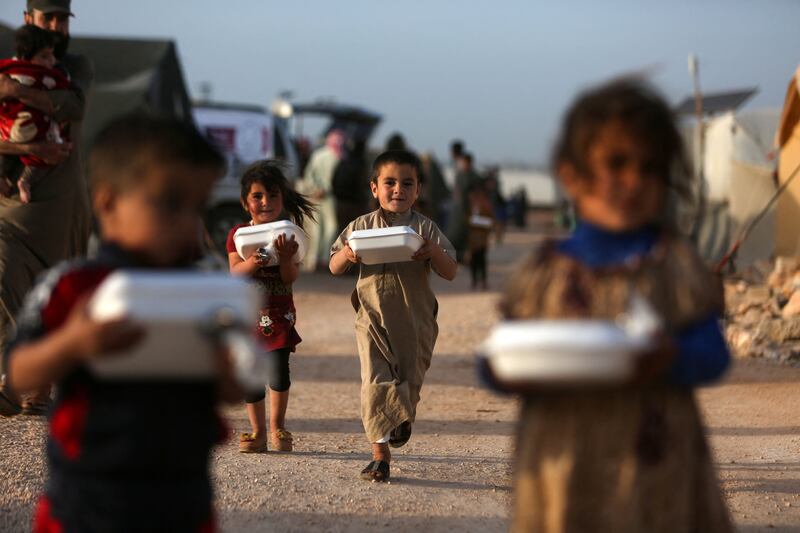 Displaced Syrian children return to their camps with boxes of food on the outskirts of the rebel-held town of Dana, in Idlib province. AFP