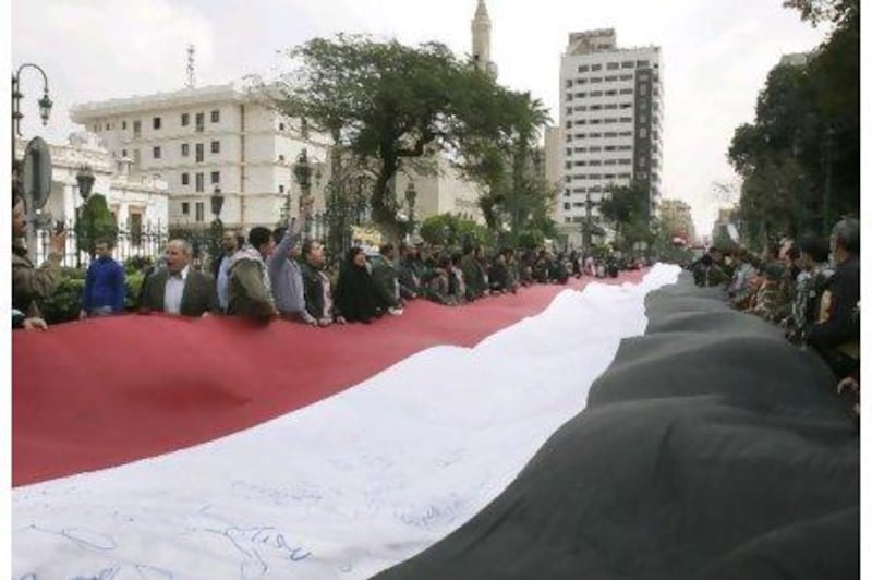 Protesters waved a giant flag near the Egyptian parliament in Cairo yesterday, while business and government leaders expressed concern about the impact of disruptions on the country's economy.