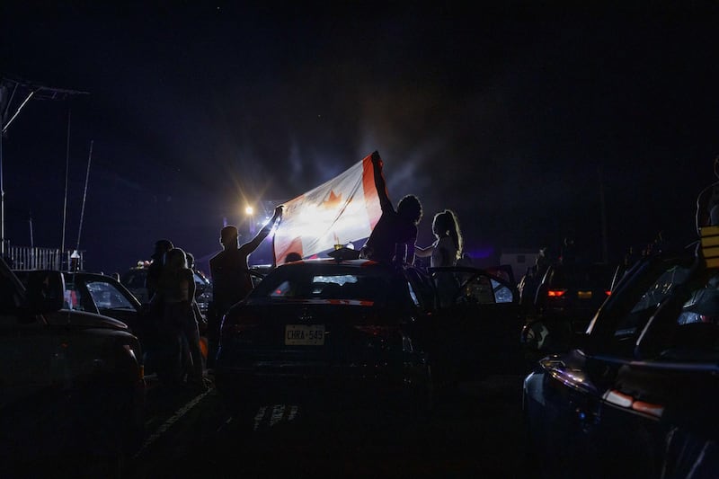 Concert-goers hold up a Canadian Flag during a singing of the Canadian national anthem during a drive-in Dean Brody concert to celebrate Canada Day in Markham, Canada. While most events marking the 153rd anniversary of Confederation across the country have been cancelled or moved online due to the spread of the coronavirus, the drive-in concert skirted social gathering rules by allowing attendees to socially distance in and on their cars. AFP