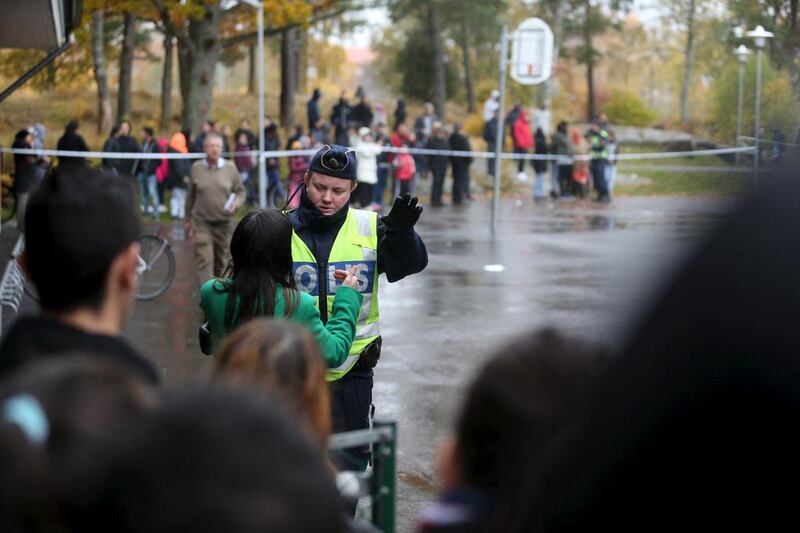 A police officer speaks to onlookers standing outside a cordoned area after a masked man attacked people with a sword at a school in Trollhattan, western Sweden on Thursday. Bjorn Larsson Rosvall / Reuters/ TT News Agency
