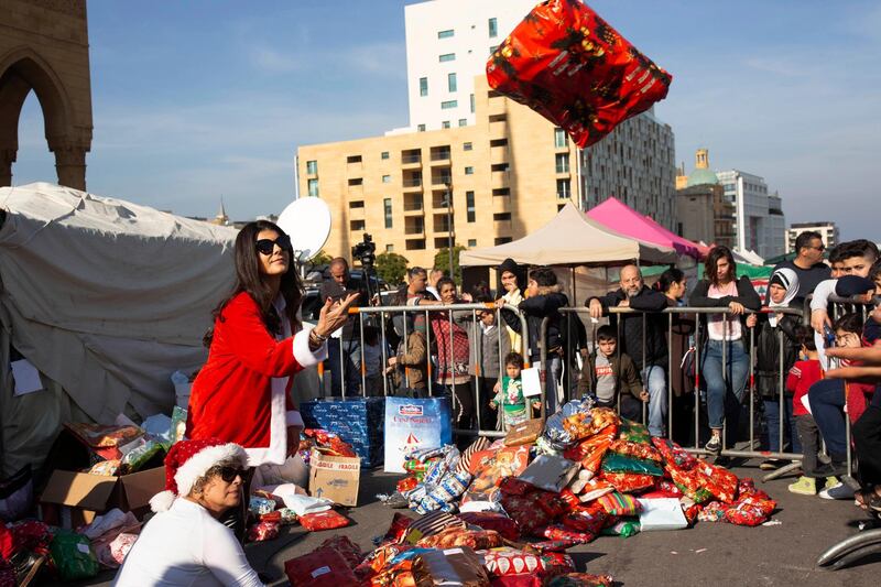 Volunteer Ibtisam Nablussi tosses a Christmas present, as anti-government protesters distribute clothing to the needy ahead of Christmas, at Martyrs Square in Beirut, Lebanon. AP Photo