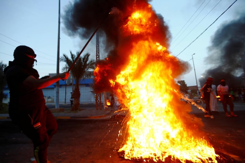 An Iraqi demonstrator burns tyres to block the road during a protest over poor public services in Najaf, Iraq. Reuters