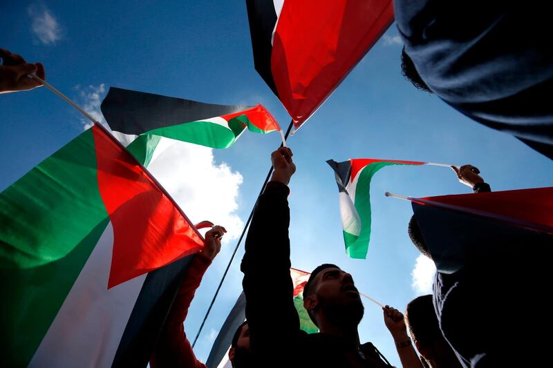 Palestinians wave national flags as they take part in a protest against a social security law proposed in the West Bank city of Ramallah. AFP