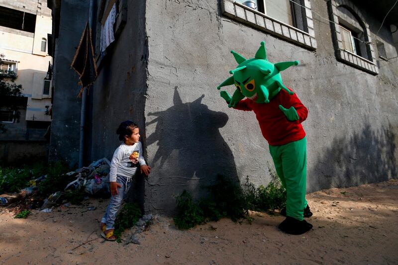 A Palestinian man wearing a coronavirus costume sewed by his sister plays with a girl in the central Gaza Strip amid the pandemic. AFP