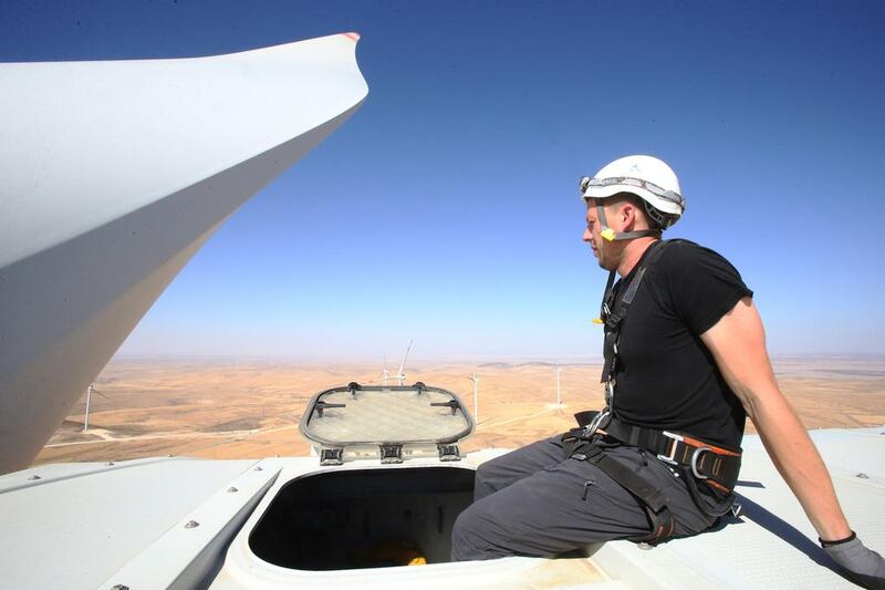 An engineer works at the top of a turbine.