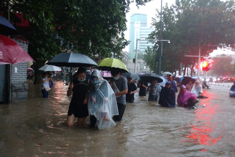 Pedestrians wade through flooding after heavy rain in Zhengzhou, the capital of China's central Henan province. Rainwater inundated the city's subway system and forced thousands of residents from their homes.