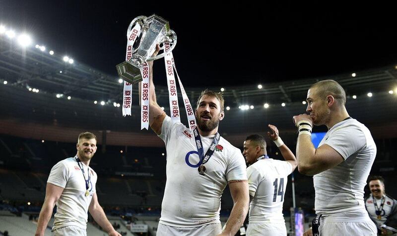 England’s flanker Chris Robshaw (C)  holds the trophy next to England’s fullback Mike Brown (R) as they celebrate winning the Six Nations rugby union tournament, after winning their match against France, at the Stade de France in Saint-Denis, north of Paris, on March 19, 2016. AFP PHOTO / FRANCK FIFE