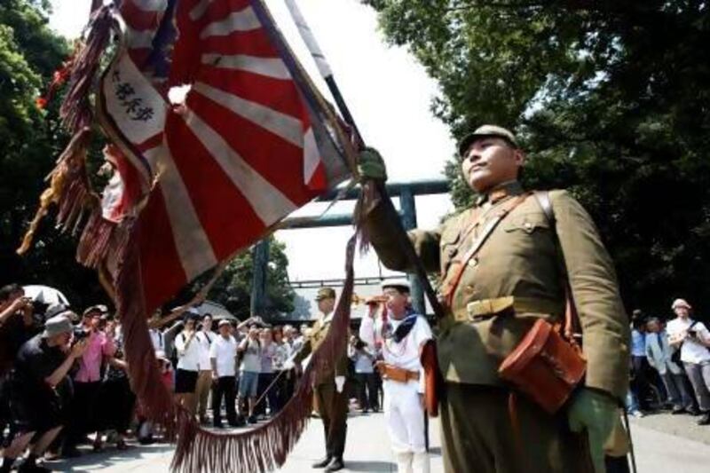 Men dressed as Japanese imperial soldiers hold Japan's rising sun flag as they march in front of the gate of the Yasukuni Shrine in Tokyo.