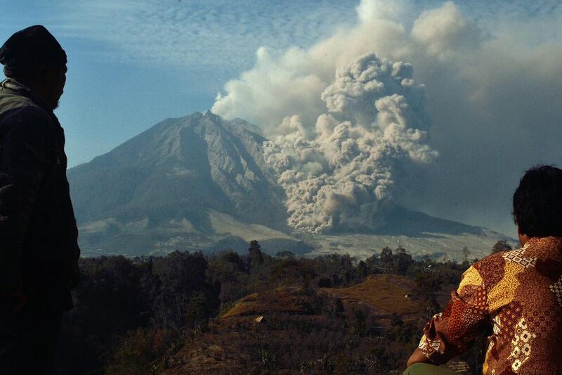 Residents watch Mount Sinabung volcano erupt in Karo district, Sumatra island, on February 12, 2014. Authorities have maintained their highest alert level since the February 1 eruption that killed 16 people. More than 30,000 people have been displaced since the volcano rumbled back to life last September. Sutanta Aditya / AFP photo