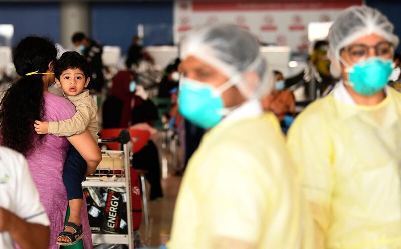 Health workers look on as Pakistani nationals check in at the Dubai International Airport before leaving the Gulf Emirate on a flight back to her country, on May 7, 2020, amid the novel coronavirus pandemic crisis.  q / AFP / Karim SAHIB
