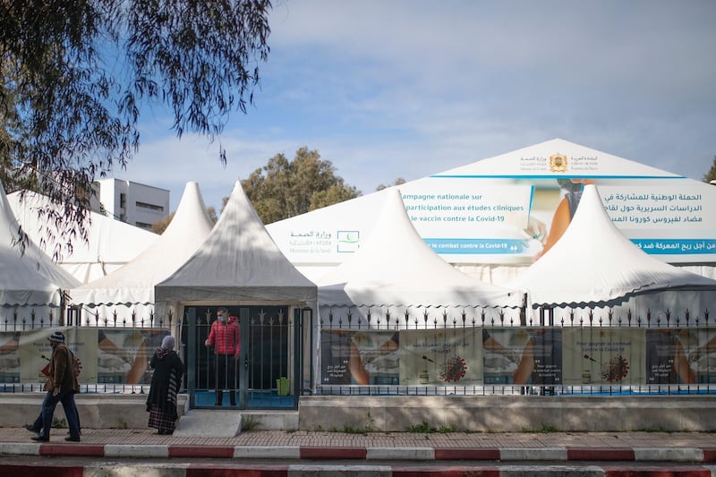 People walk past a bivouac where clinical trials for covid-19 vaccines are conducted, in Rabat, Morocco, Monday, Dec. 7, 2020. (AP Photo/Mosa'ab Elshamy)