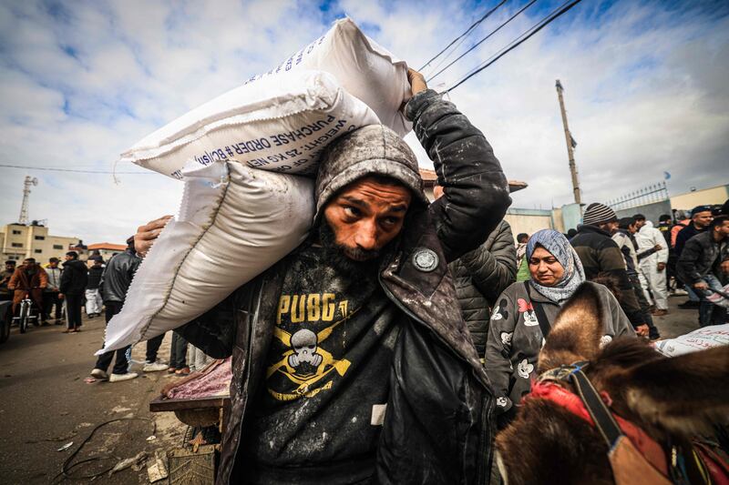 Displaced Palestinians receive bags of flour and other food aid at the UNRWA centre in Rafah, southern Gaza. AFP