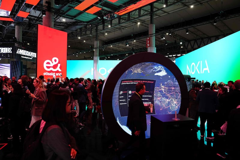 Visitors pass the stand of UAE global technology company e& at the Mobile World Congress in Barcelona. The major industry event is focusing on AI-powered innovations. AFP