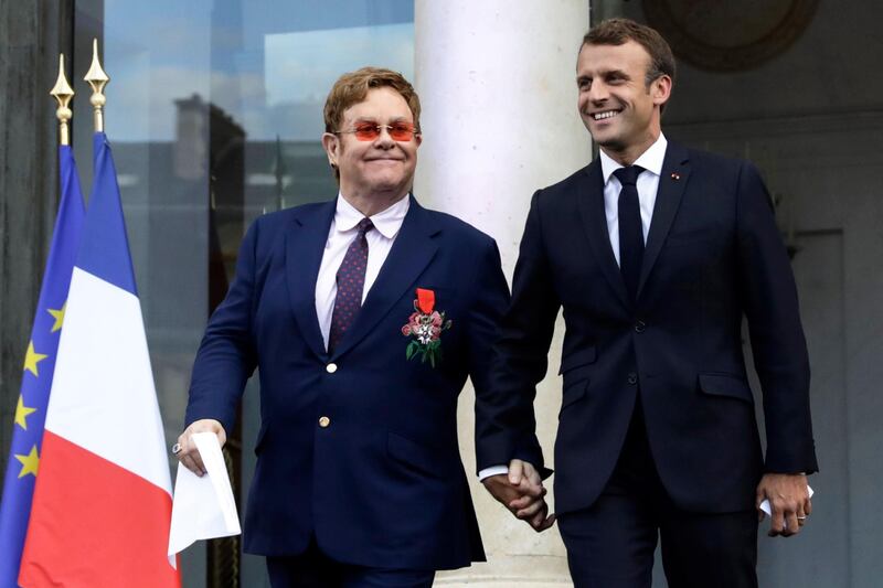 TOPSHOT - French President Emmanuel Macron (R) and British singer-songwriter Elton John arrive to speak to a crowd in the courtyard of the Elysee Palace in Paris, on June 21, 2019, as part of a ceremony to award John of the French Legion of Honour and concerts to mark France's annual "Fete de la Musique" (Music Festival). 

  / AFP / POOL / POOL / LEWIS JOLY
