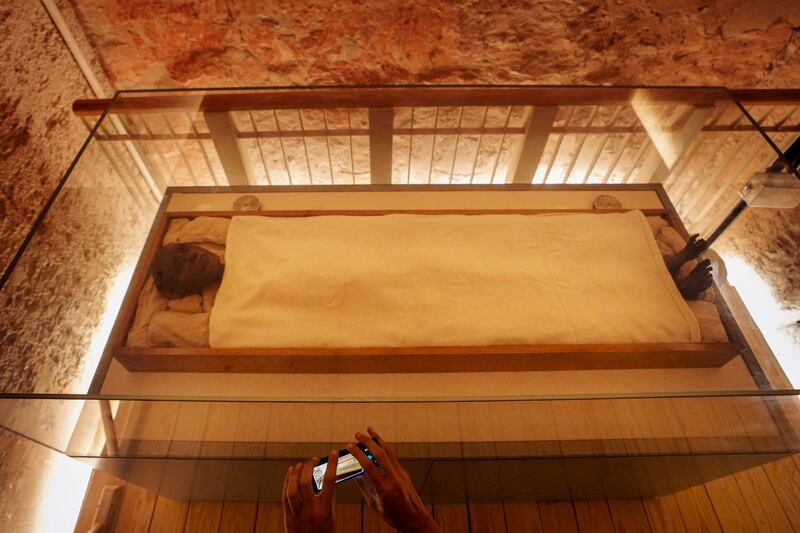 A tourist films Tutankhamun's mummy in his tomb chamber. AP Photo