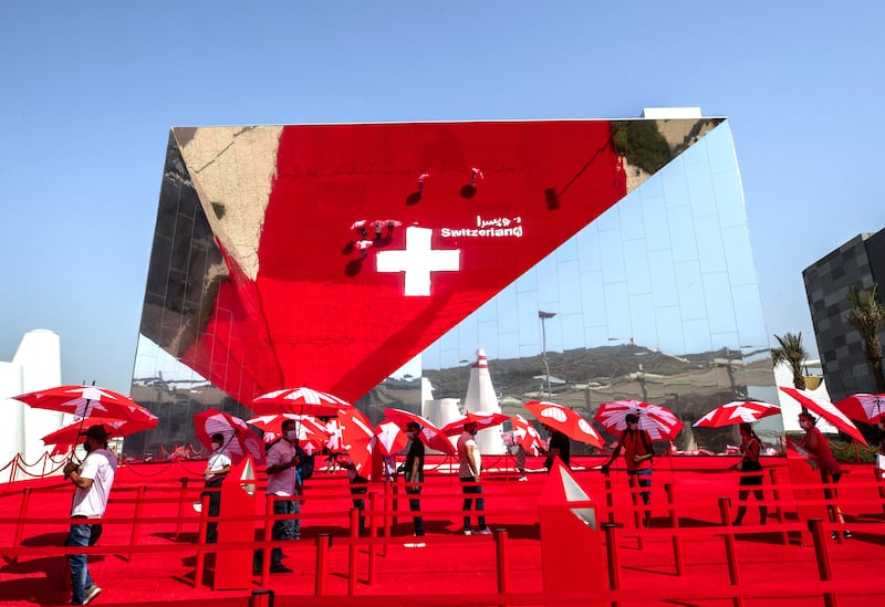 Visitors to the Switzerland pavilion take shade under umbrellas while waiting in line. Victor Besa / The National