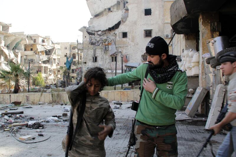 Syrian youth Ahmed, 13-years old (L) and Faris (R), 16-years old, who allegedly fight alongside opposition fighters from the Sadeq Al-Amin Brigade, get prepared with another member of the brigade before a patrol in the Salah al-Din neighbourhood of the northern Syrian city of Aleppo on November 17, 2013. For three weeks, the army has been pressing a campaign to retake rebel-held areas in Aleppo, particularly east of the country's second city, and jihadist fighters have called for mass mobilisation to counter regime advances. AFP PHOTO / KARAM AL-MASRI (Photo by KARAM AL-MASRI / AFP)