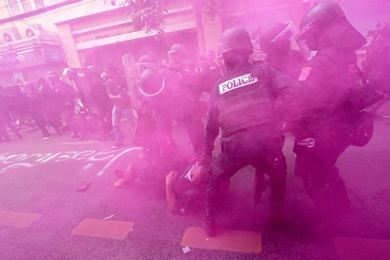 In cloud of pink smoke, police in riot gear remove a protester trying to march to the Asia-Pacific Economic Co-operation summit venue in Bangkok, Thailand. AP Photo