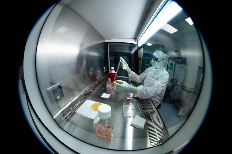 A lab technician wearing personal protective equipment performs tests under a hood, using reagent bottles at a French pharmaceutical company Sanofi's laboratory in Val de Reuil.   AFP