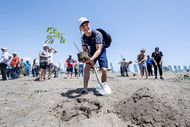French wrestler Quentin Jean-Rene Sticker plants a tree as part of a climate project at the UWW Beach Wrestling World Series at Sarigerme.
