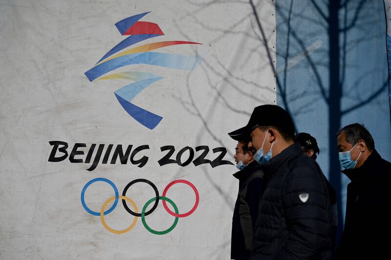 People walk past the Beijing 2022 Winter Olympics logo at the Shougang Park in Beijing.  AFP