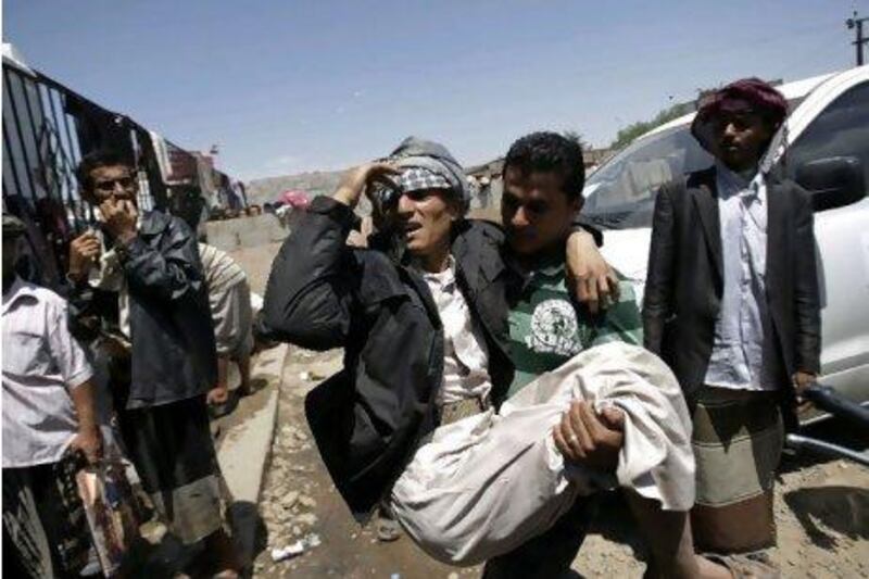 Anti-government protestors carry a wounded man from the site of clashes with security forces, in Sanaa yesterday. Hani Mohammed / AP Photo