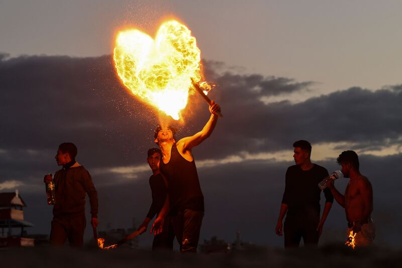 Palestinian youth show their fire breathing skills along the beach in Gaza City, on January 13, 2023.  (Photo by MOHAMMED ABED  /  AFP)