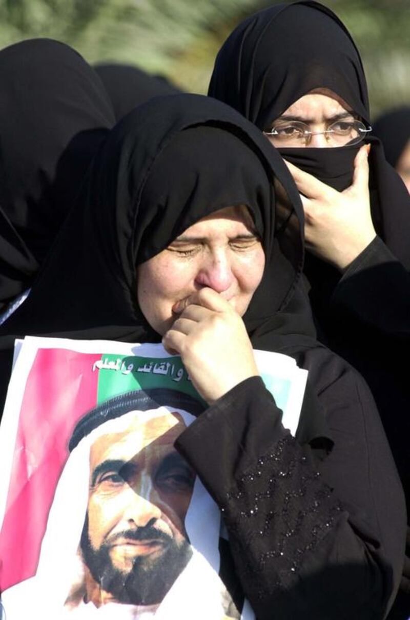 Mourners carry photos of Sheikh Zayed while standing in the streets on the day of the UAE Founding father's funeral
