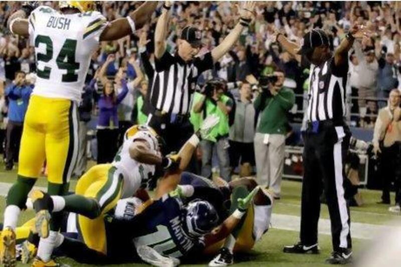 Interception and touchback? One official signaled just that but another signaled a touchdown by Seattle Seahawks wide receiver Golden Tate, obscured, on the last play of the NFL game against the Green Bay Packers.